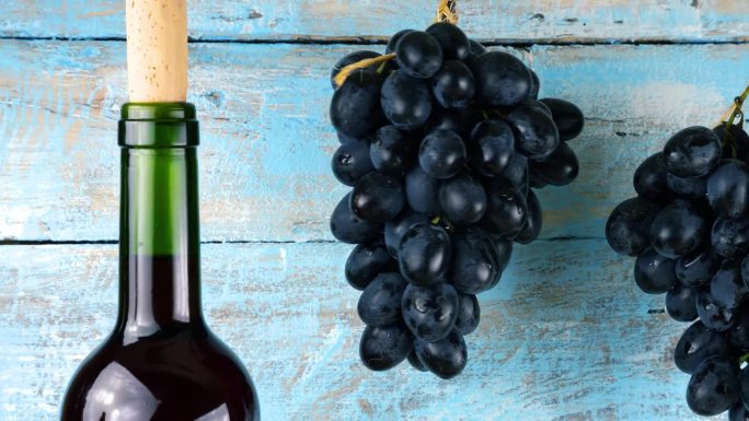 葡萄和酒瓶在蓝色的复古木制背景。
