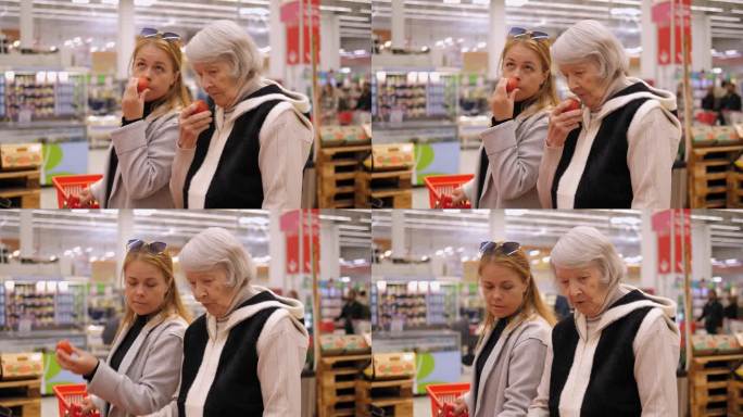 一位老太太和孙女在超市里闻苹果。
