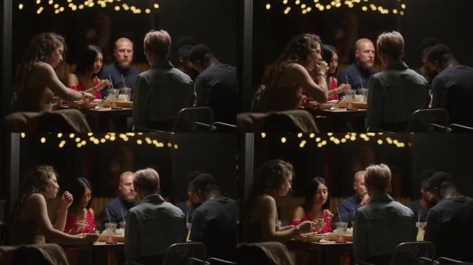 不同种族、不同年龄的人晚上一起在餐厅吃饭，多民族的男人和女人