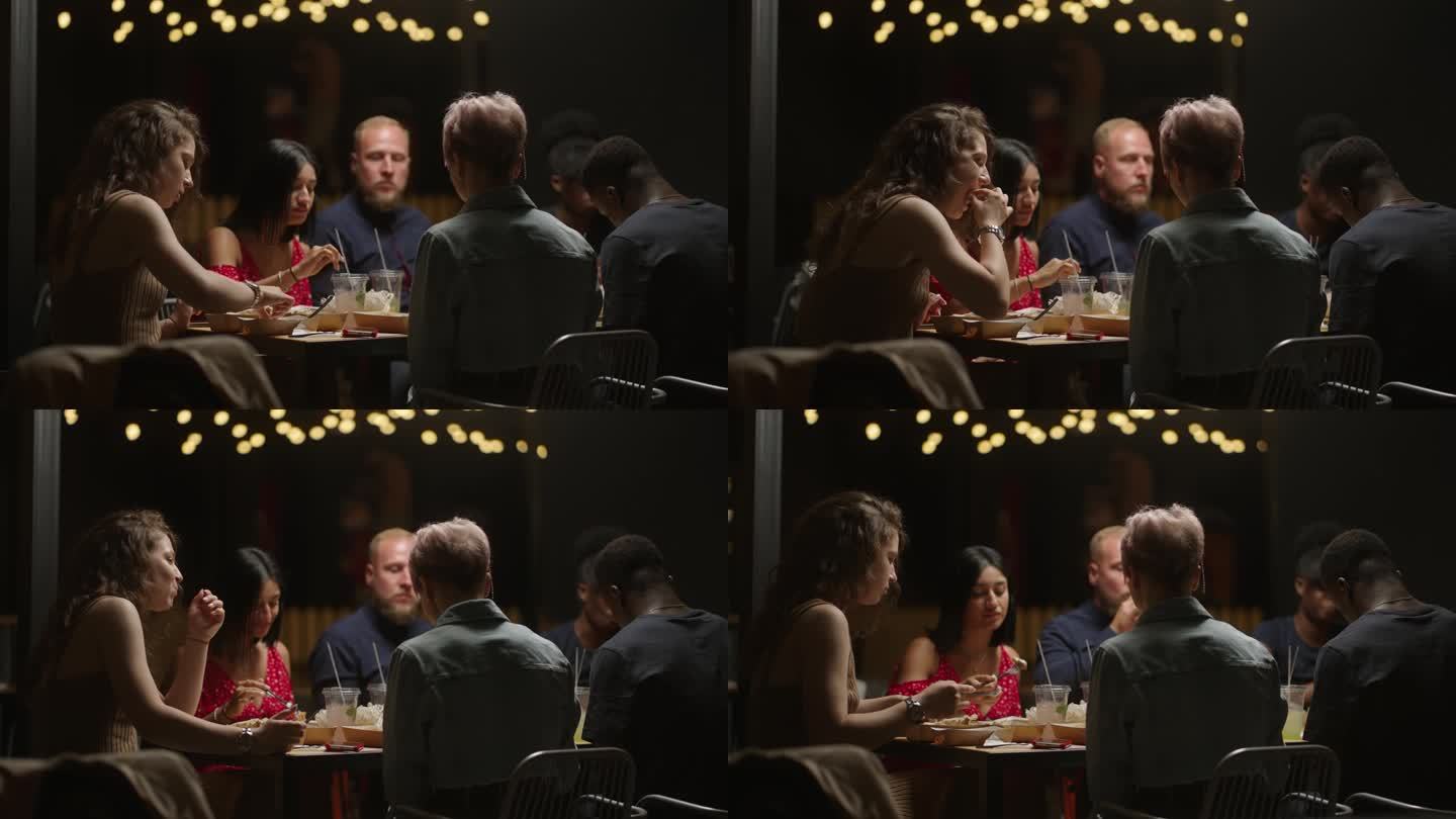 不同种族、不同年龄的人晚上一起在餐厅吃饭，多民族的男人和女人