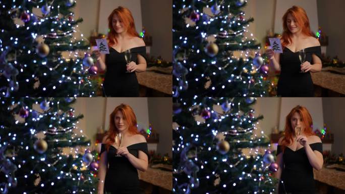 一位身穿鸡尾酒会礼服的美丽年轻女子站在圣诞树旁，手里拿着一杯香槟，读着一张新年贺卡。喝香槟是实现愿望