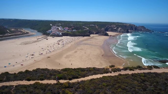 游客沿着小路散步，无人机拍摄了葡萄牙奥德赛阿连特约村附近的海湾和海滩。