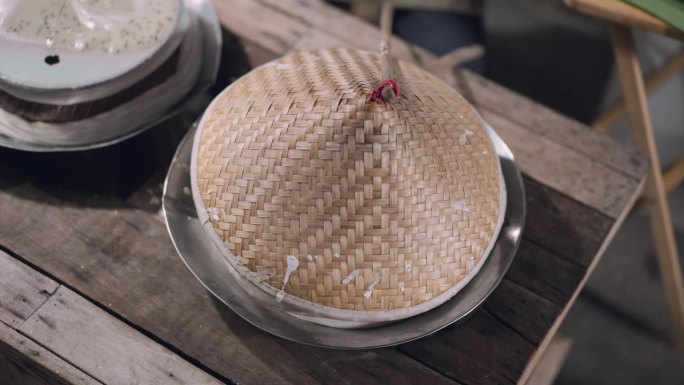 俯视图，当地人将制作甜点的白色液体原料倒入蒸锅中，用木盖盖上蒸锅，使其凝固，然后在当地市场的摊位上用