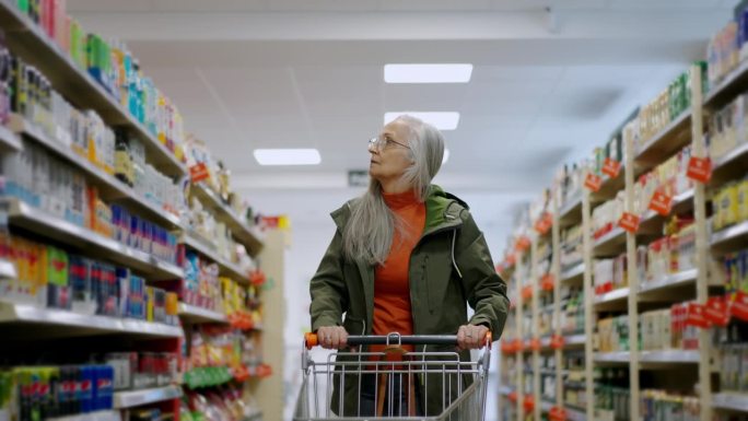 老妇人推着空手推车在超市购物，通货膨胀和物价上涨的概念。