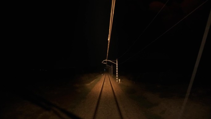 黑夜里，电线杆附近，车头灯和空轨道的行驶火车