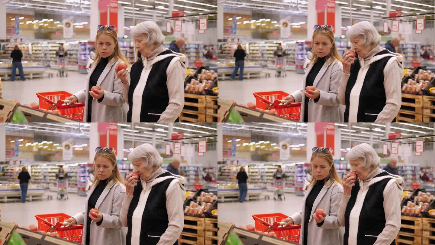 一位老太太和孙女在超市里闻苹果。