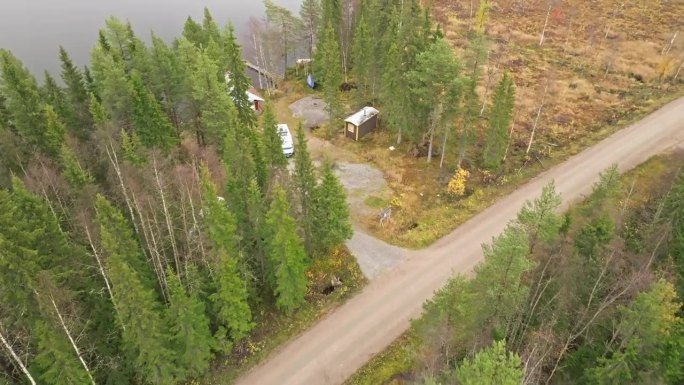 秋天，一辆露营车停在瑞典的湖边，杉木林中的一条路。无人机航拍