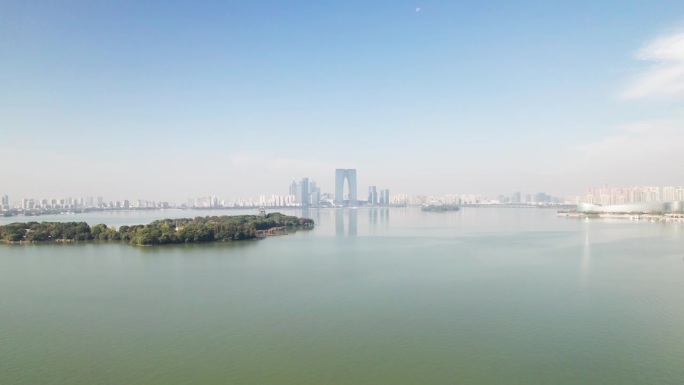 无人机在中国江苏省苏州市金鸡湖上空飞行。在阳光明媚的秋日，从空中俯瞰苏州美丽的湖景和地标，4k实时镜