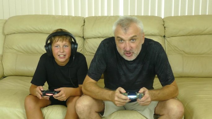 一个满头白发的男人和一个男孩激情地玩着电脑游戏