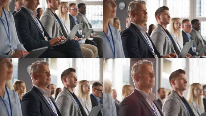 一名白人男子在商务会议上坐在拥挤的听众中使用笔记本电脑。公司代表观看关于发展市场、金融机会的创业演讲