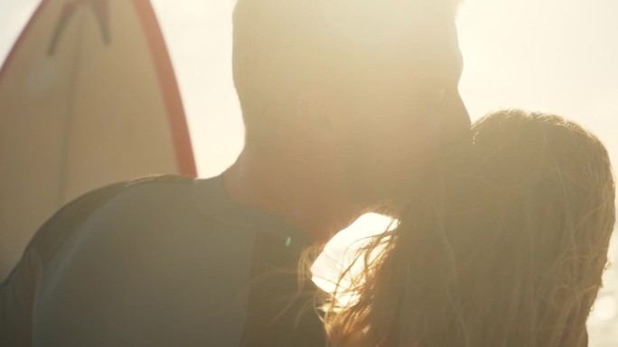 快乐，深情的冲浪夫妇在阳光明媚的海滩上接吻