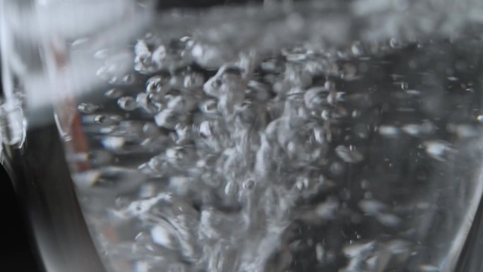 超慢速视频:将清澈的液体倒入双层玻璃杯中