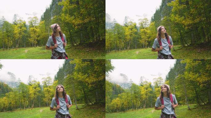 快乐的女人在秋天的森林里徒步旅行，敬畏地看着风景