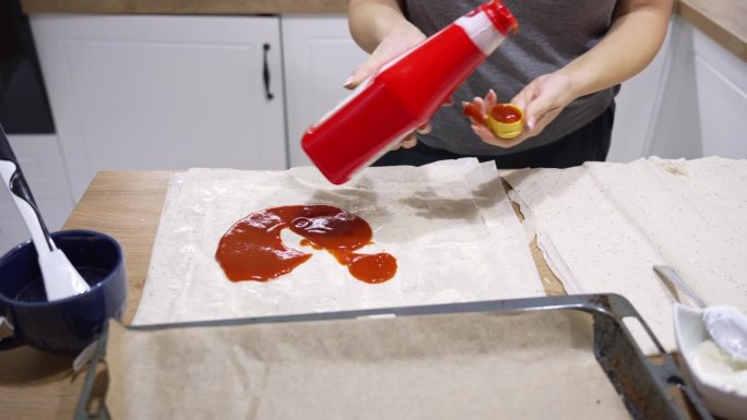 一个白人女人在厨房里做美味派的时候把番茄酱涂在派皮上