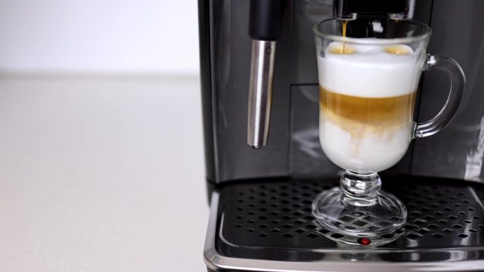 咖啡机把咖啡倒入有奶泡的杯子里。