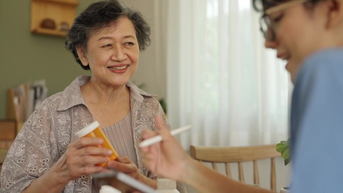一位女护工在家照顾一位老妇人的药物。