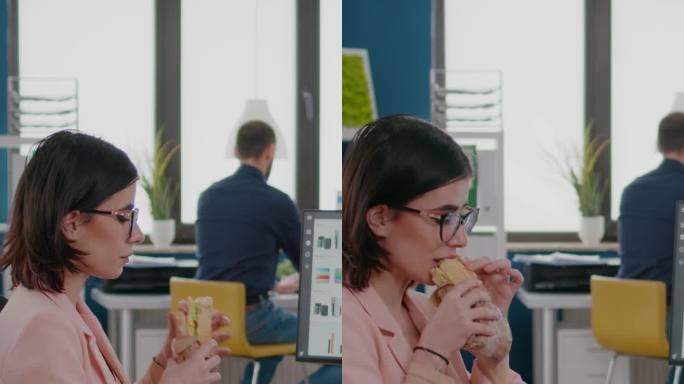 垂直视频:在商业公司工作的女商人吃着美味的三明治