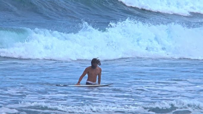 男子冲浪者与冲浪板在海上自然和海浪的背景。海岸边沙滩上的冲浪板不见了。海滨海湾的肖像男转向游泳或冲浪