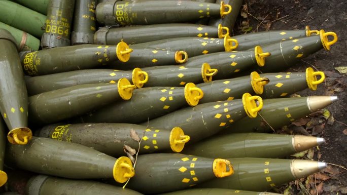 战场上的草地上有155口径的炮弹。重型武器的弹药。