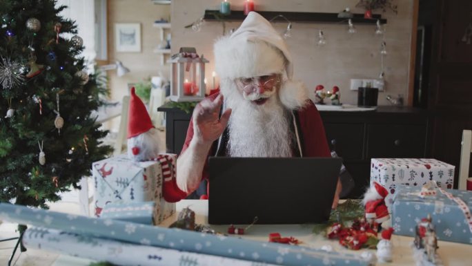 圣诞老人在家里对着笔记本电脑挥手