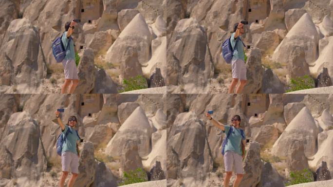 一名年轻的游客探索着讲述土耳其卡帕多西亚古老故事的非凡岩层。这些超现实的岩石，曾经是古代居民雕刻的家