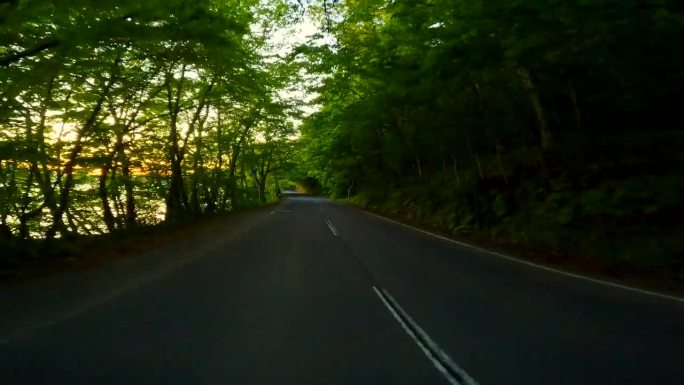 日落时沿着湖边的公路行驶