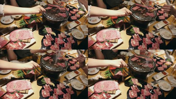 一名年轻的亚洲女子在一家餐馆里吃着传统的日式牛肉烧烤“Yakiniku”，并把生牛肉片放在木炭烤炉上