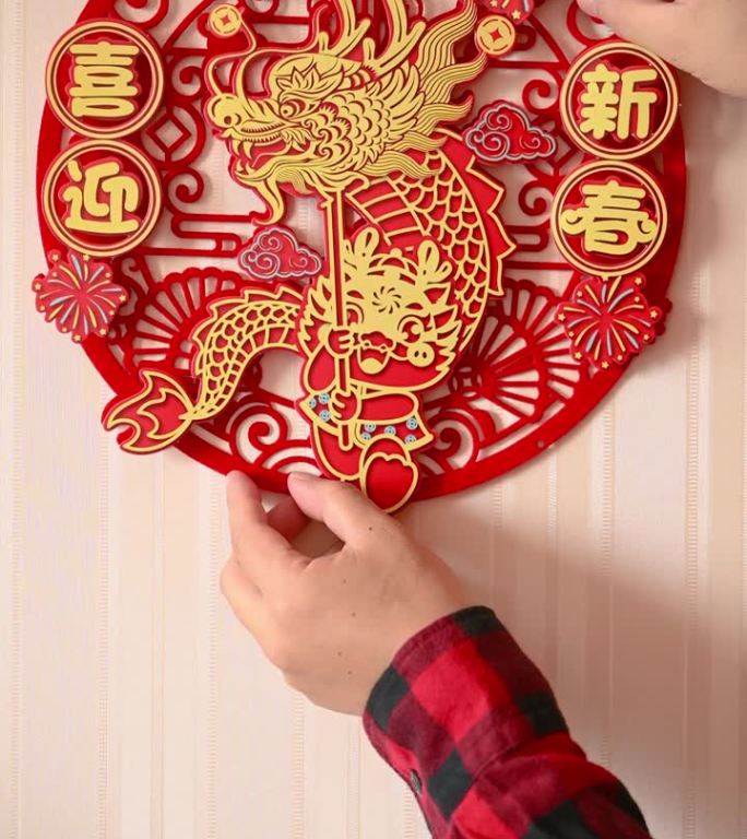 男子在一扇门上贴了一个中国新年的龙年装饰，在垂直的构图翻译的中文字样是吉祥和欢迎新的一年没有标志没有