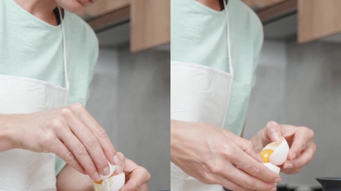 一个女人正在明亮的厨房里做饭。她打了一个鸡蛋，把蛋清和蛋黄分开放进玻璃杯里。垂直视频。