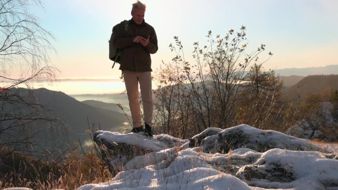 一个成熟的男人徒步穿过白雪皑皑的高山草地