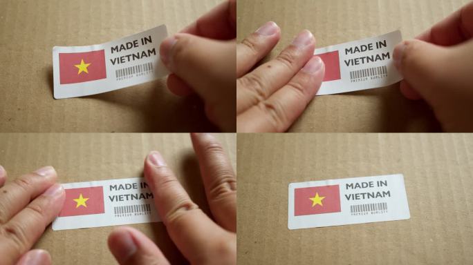 手将“越南制造”国旗标签贴在带有产品优质条形码的运输箱上。制造和交付。产品出厂进出口。