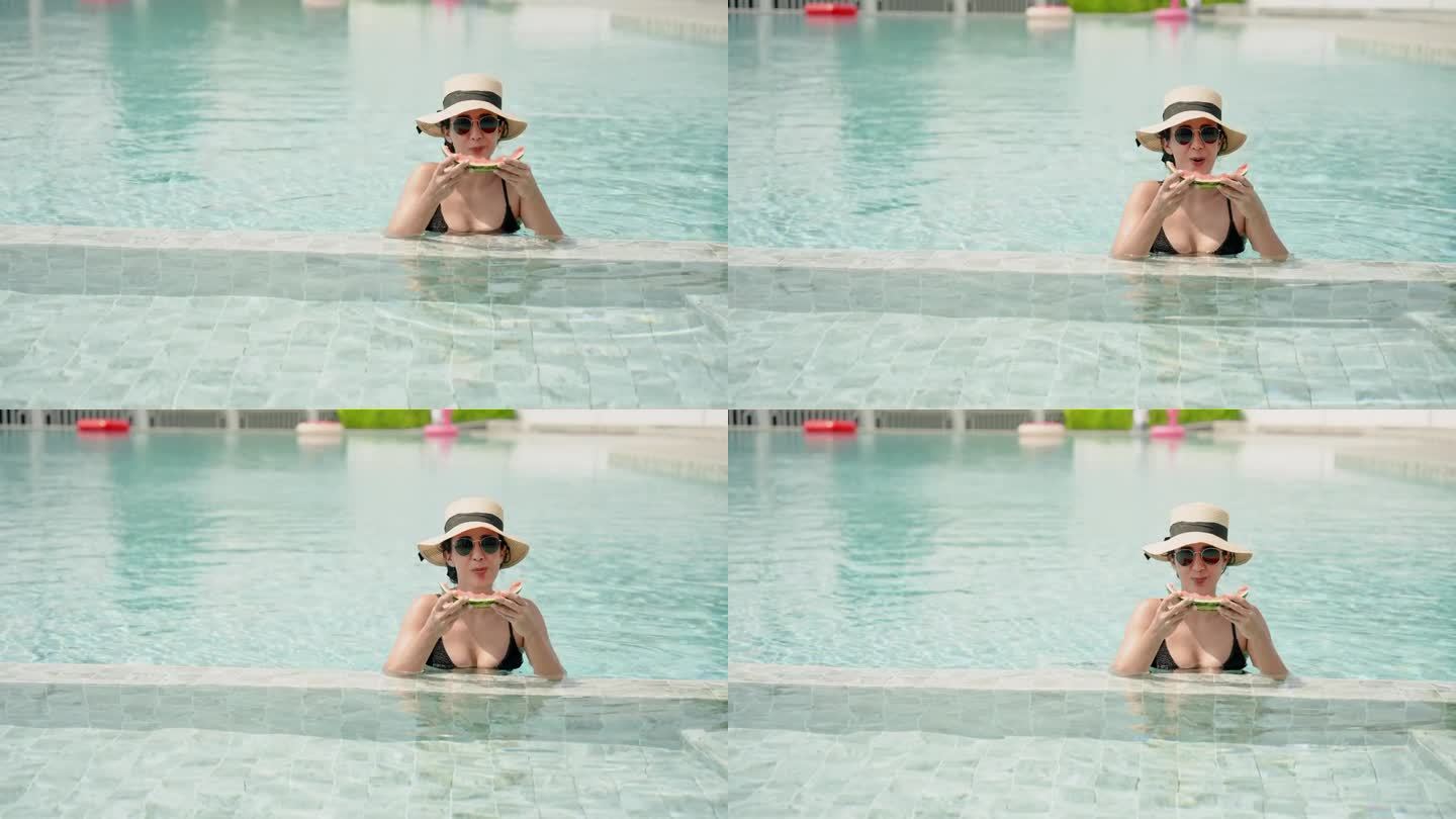 美丽的西班牙女孩站在水里，在池塘里愉快地吃西瓜，穿着泳衣晒太阳，在游泳池里戴上帽子和太阳镜。在一个炎
