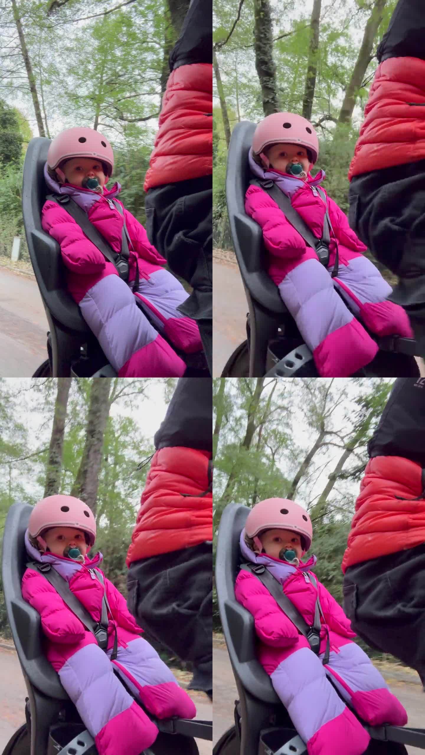 婴儿在冬天穿着蓬松的保暖衣服骑在自行车座位上