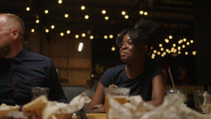 快乐的非裔美国妇女在餐厅的周末聚会上与朋友谈笑风生