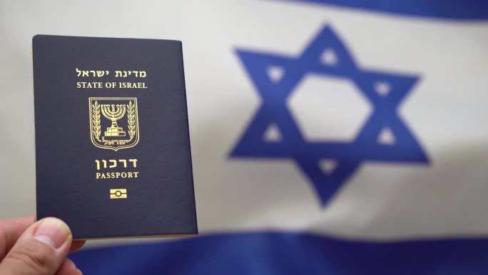 手拿着以色列国际护照，对着风中飘扬的以色列国旗