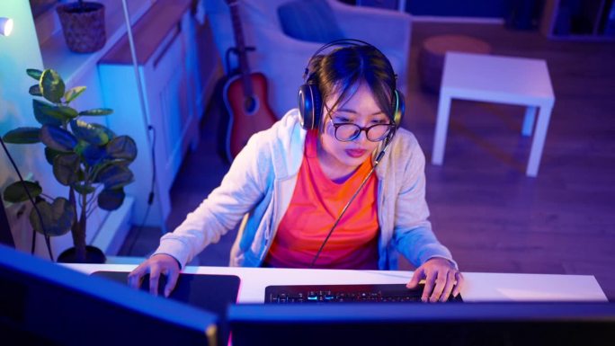 亚洲女性玩家，在PC上玩视频游戏时直播自己