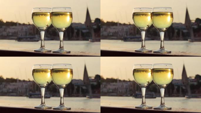 两杯白葡萄酒，以河景和船只为背景