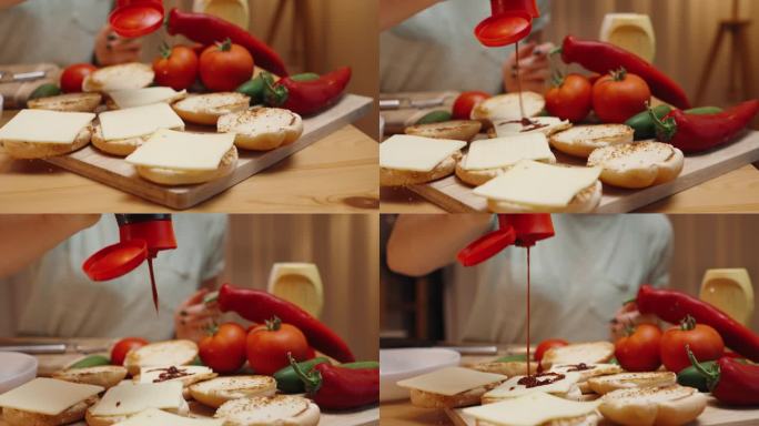 在温馨的夜晚，一位女士在准备汉堡。她把酱汁淋在已经放在面包上的奶酪上。慢镜头，特写镜头。