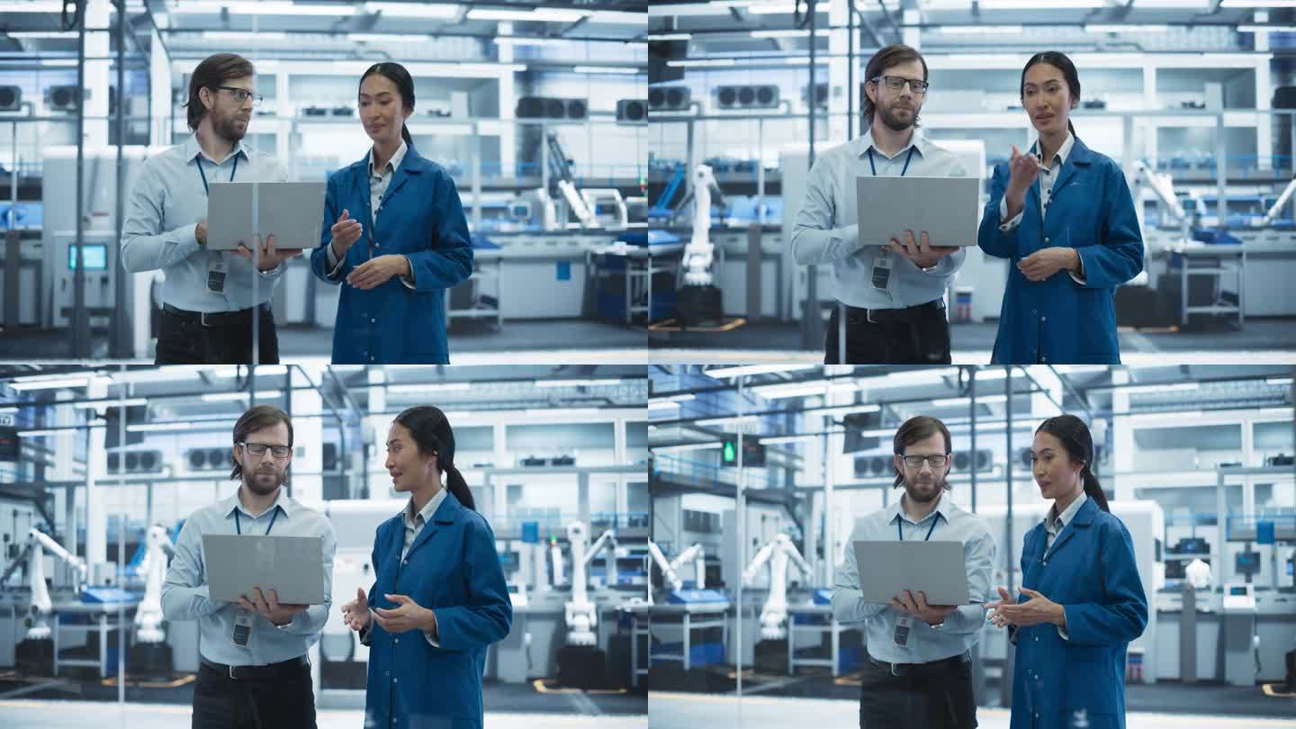 一名白人男子和一名亚洲女子在工业设施内交谈。先进的工厂员工协同工作，使用笔记本电脑监督工厂的工作过程