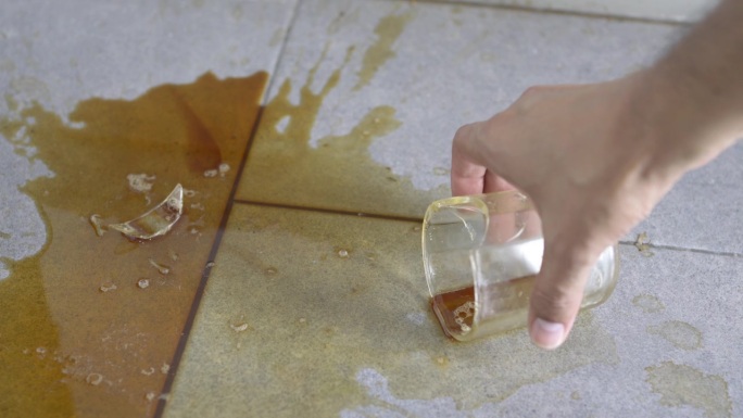 手握着一杯碎咖啡损坏弄脏地面捡起杯子