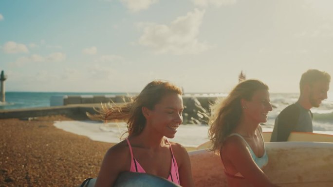 冲浪的朋友们在阳光明媚的海滩上拿着冲浪板散步