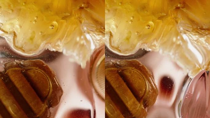 人们喜欢甜食的概念:一个男人用手指舔着盘子里的蜂蜜，从下面透过蜂蜜和透明玻璃看到的不寻常的景象。特写