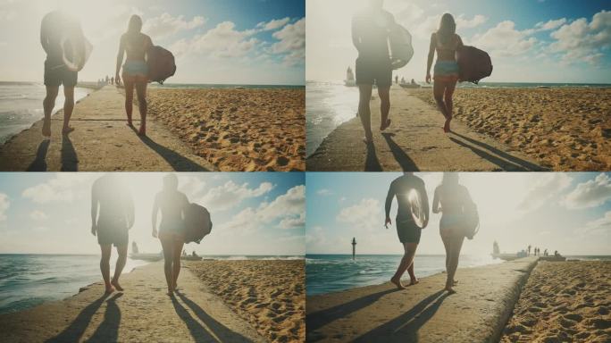 冲浪夫妇在阳光明媚的海滩上带着冲浪板散步