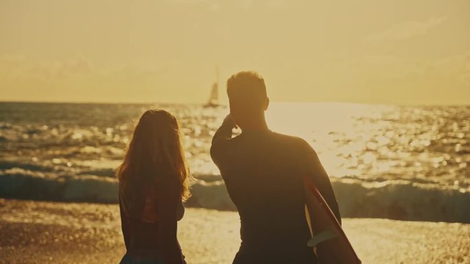 夕阳下，一对冲浪夫妇在阳光明媚的海滩上拥抱