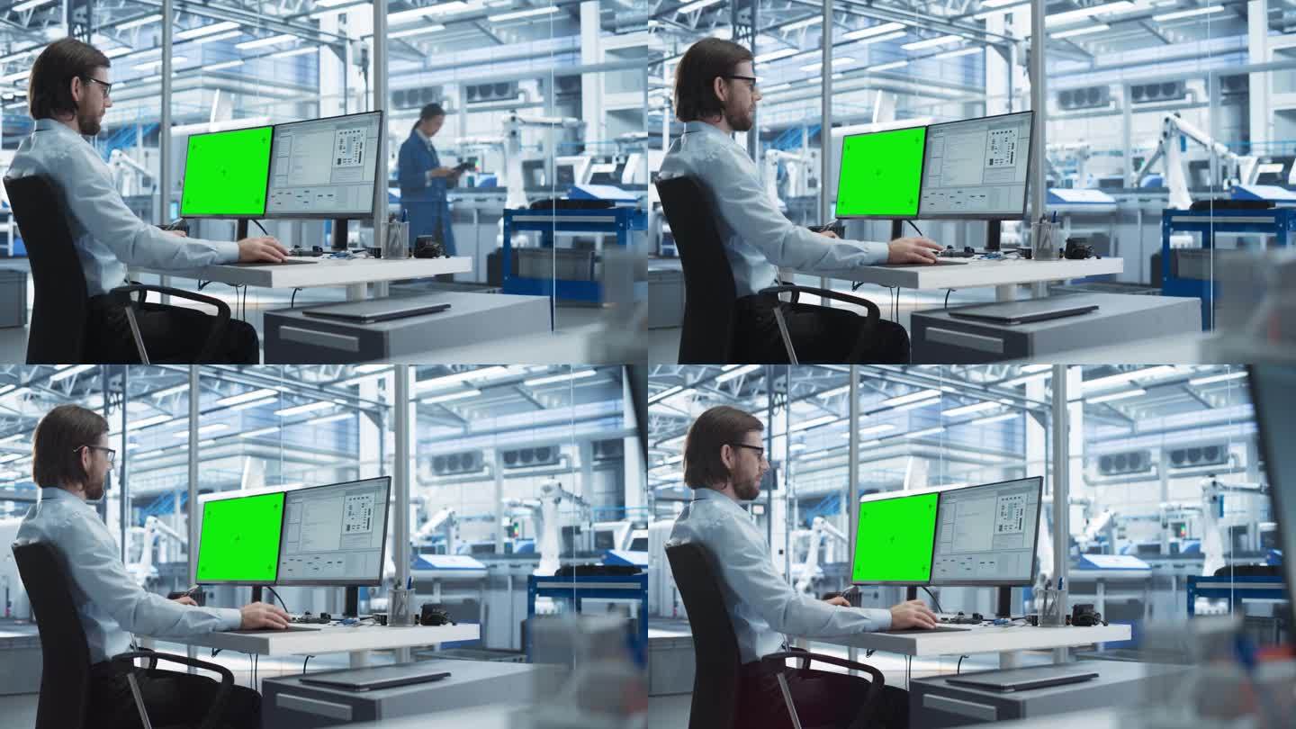 年轻的软件开发人员在工厂办公室里使用绿屏Chromakey模拟显示器的台式电脑工作。技术研发工厂，配
