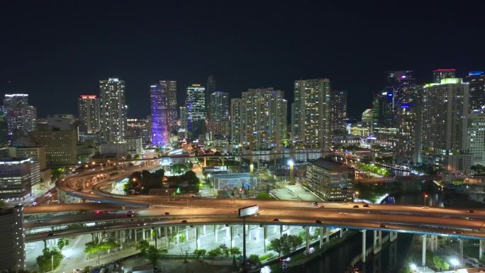 上图是佛罗里达州迈阿密市宽阔的高速公路十字路口，夜晚汽车疾驶。美国交通基础设施概念