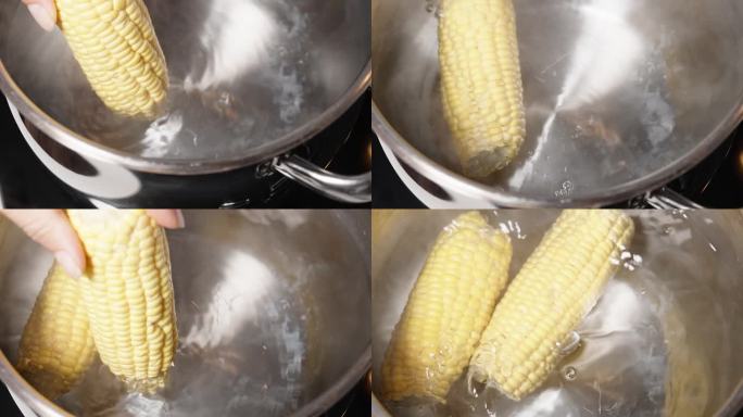 我把两根玉米棒扔进沸水里。从顶部看，慢动作，用摄影车拍摄。