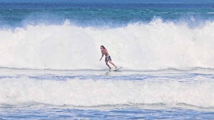 一个冲浪者在美丽的海浪上冲浪，慢动作。酷天堂冒险休闲岛。阳光明媚的一天，冲浪者在蓝色的大洋。专业健康