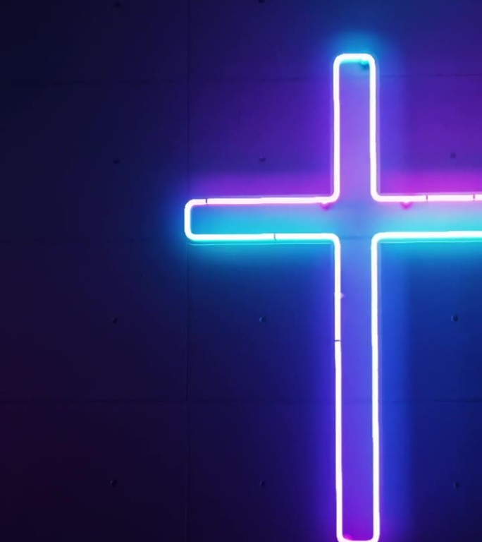 明亮的霓虹色调在教堂的墙上创造了一个生动的基督教十字架。
