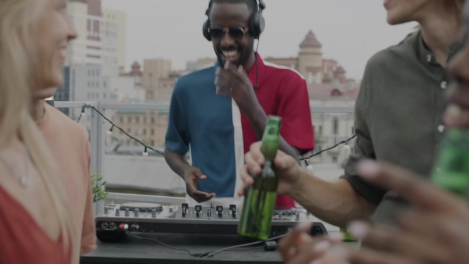 精力充沛的DJ混合着音乐，青年男女在屋顶上喝着酒跳舞